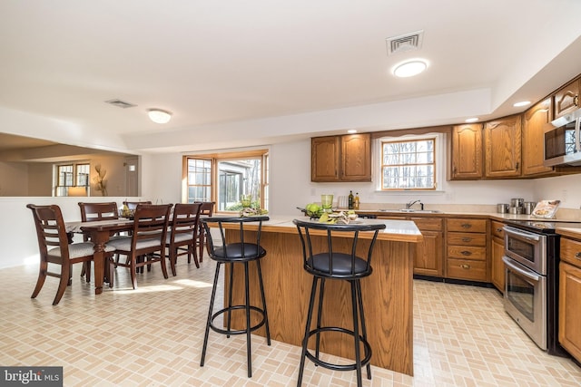 kitchen featuring stainless steel appliances, a kitchen island, plenty of natural light, and a breakfast bar area