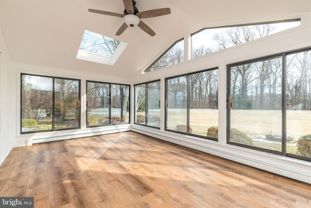 unfurnished sunroom with ceiling fan, lofted ceiling with skylight, a wealth of natural light, and a baseboard heating unit