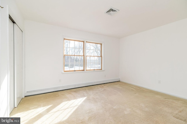 unfurnished bedroom with a closet, light colored carpet, and a baseboard radiator