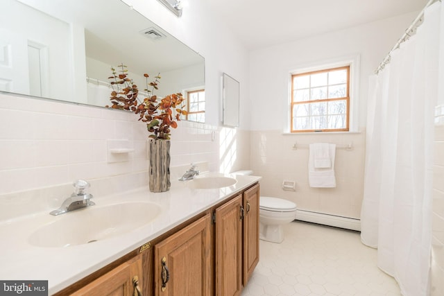 bathroom featuring a healthy amount of sunlight, toilet, tile walls, and a baseboard heating unit