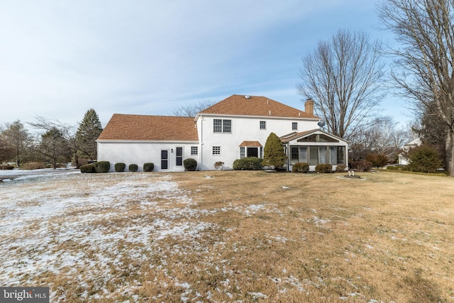 back of house featuring a lawn and a sunroom