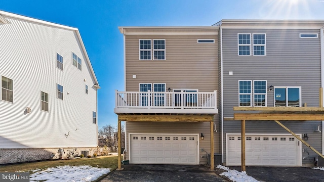 snow covered rear of property featuring a garage