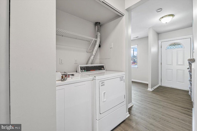 clothes washing area featuring washer and clothes dryer, laundry area, light wood-type flooring, and baseboards