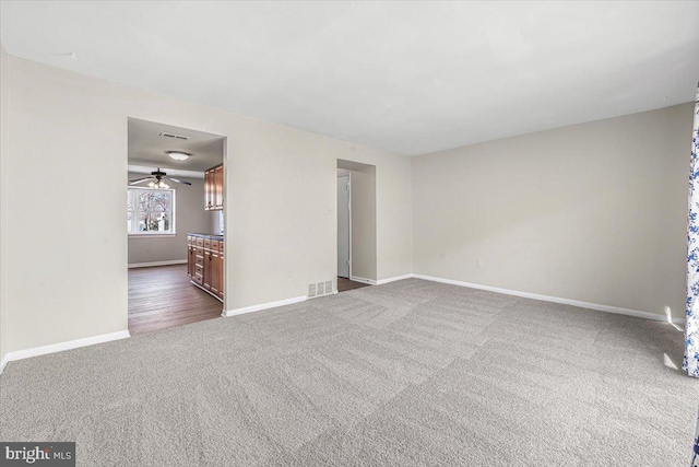 spare room featuring visible vents, dark carpet, and baseboards