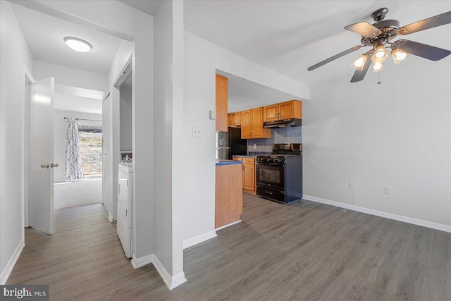 kitchen featuring black appliances, light wood-style flooring, baseboards, and under cabinet range hood