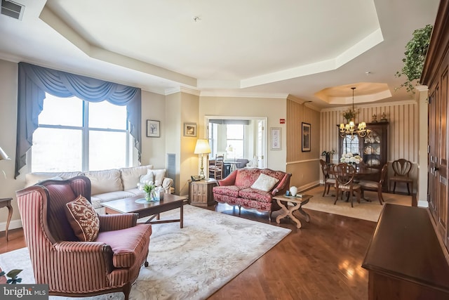 living room featuring dark hardwood / wood-style flooring, a notable chandelier, and a raised ceiling