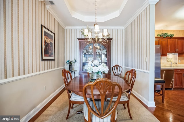 dining space with dark wood-type flooring, a notable chandelier, and a tray ceiling