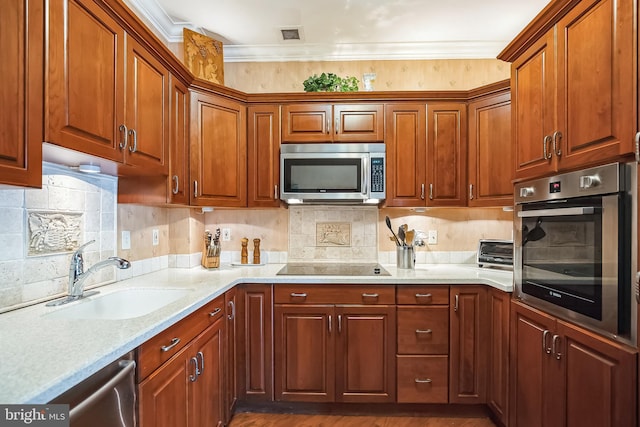 kitchen with sink, light stone counters, ornamental molding, appliances with stainless steel finishes, and decorative backsplash