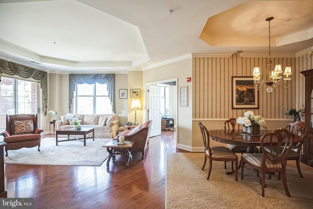 dining room with crown molding, dark hardwood / wood-style floors, a raised ceiling, and a notable chandelier