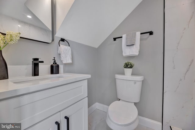 bathroom featuring vanity, toilet, and vaulted ceiling