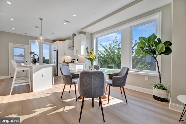 dining space with light wood-type flooring and sink