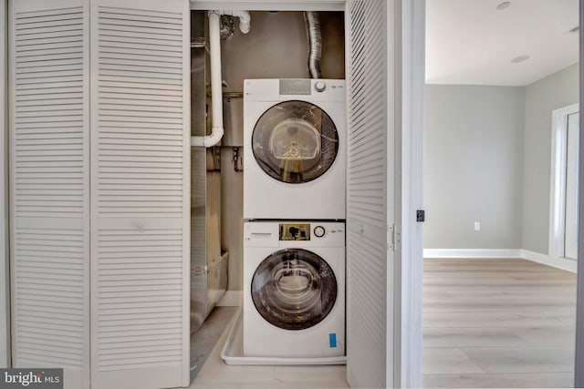 laundry room featuring stacked washer and dryer and light wood-type flooring