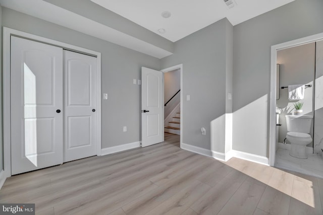 unfurnished bedroom featuring connected bathroom, a closet, and light hardwood / wood-style floors