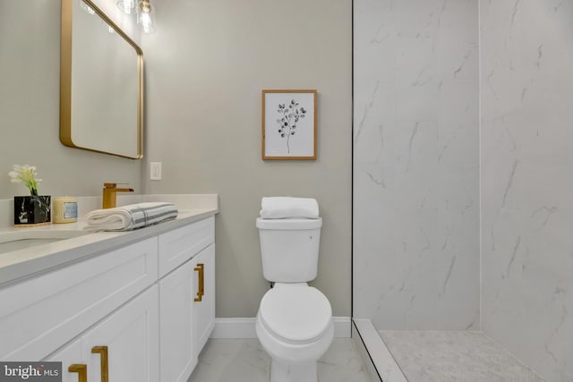 bathroom with a tile shower, vanity, and toilet