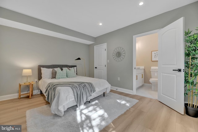 bedroom with connected bathroom and light hardwood / wood-style floors