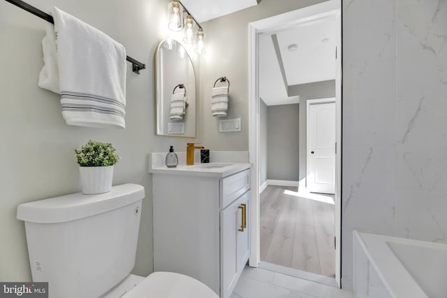 bathroom with vanity, toilet, and a tub