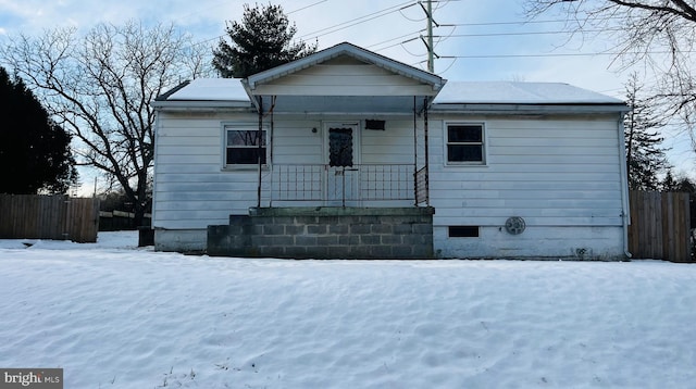 snow covered back of property with covered porch