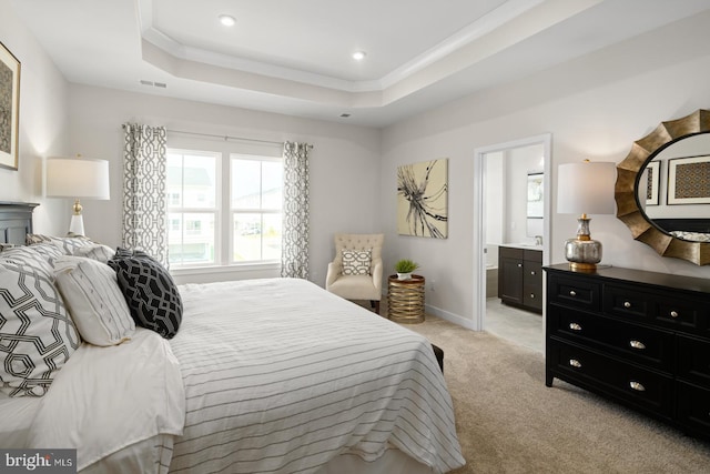 carpeted bedroom with sink, a tray ceiling, and ensuite bathroom