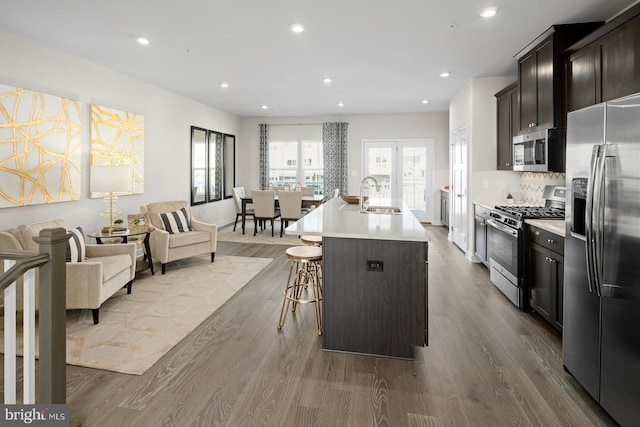 kitchen featuring wood-type flooring, sink, a breakfast bar area, stainless steel appliances, and a center island with sink