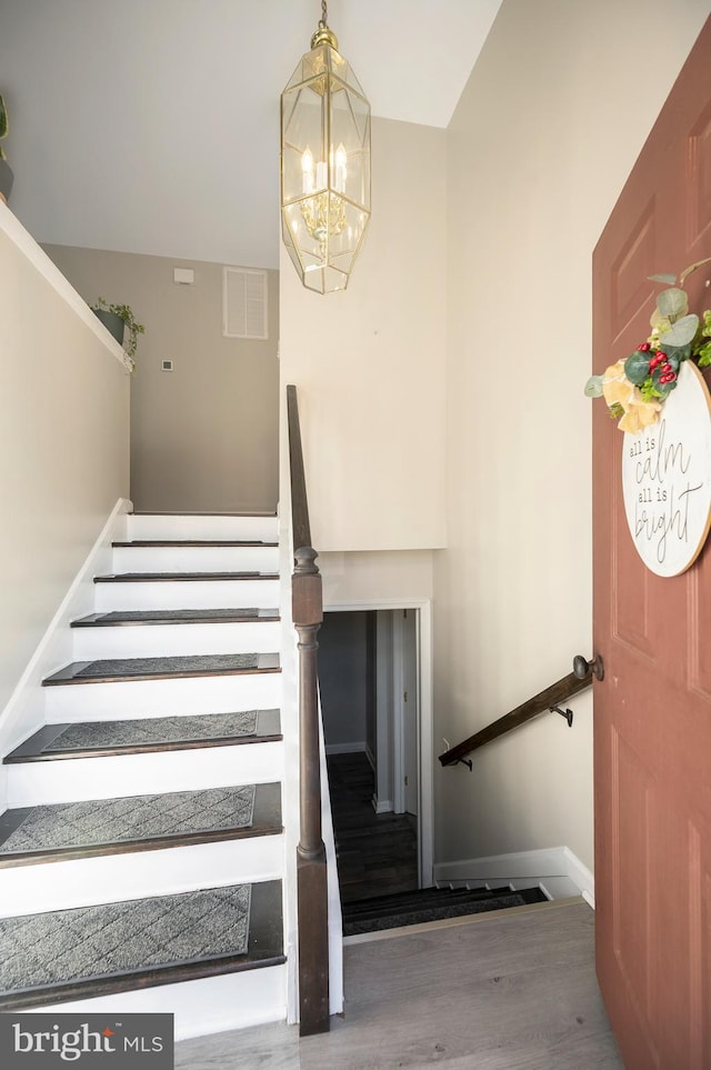 stairs with a notable chandelier and wood-type flooring