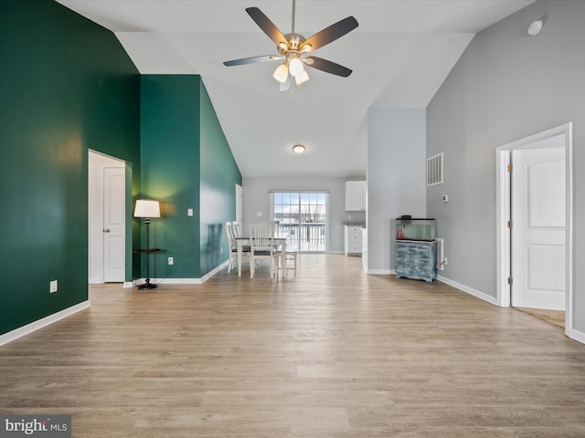 unfurnished living room featuring ceiling fan, high vaulted ceiling, and light wood-type flooring