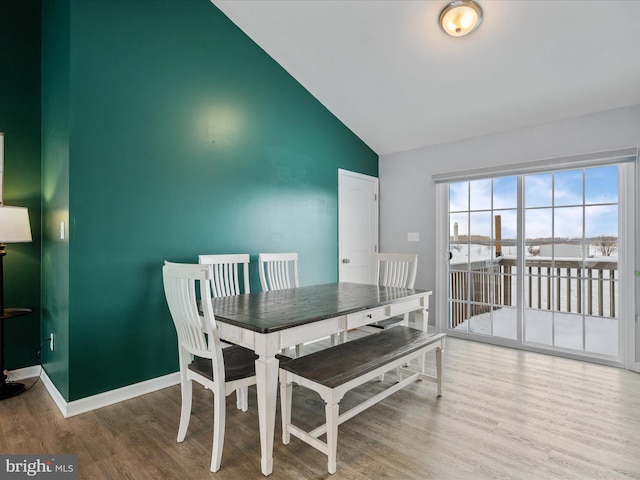 dining area with wood-type flooring and vaulted ceiling