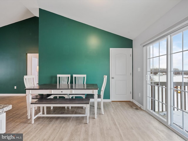 dining area featuring high vaulted ceiling and light hardwood / wood-style flooring