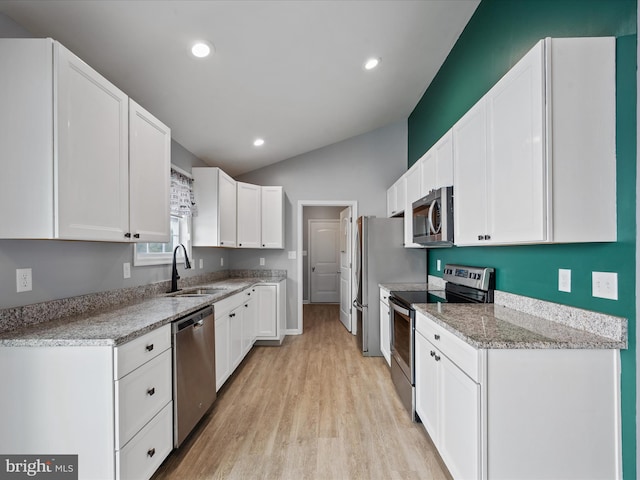 kitchen featuring white cabinetry, sink, vaulted ceiling, and stainless steel appliances