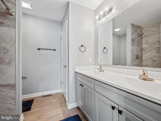 bathroom with tiled shower, wood-type flooring, and vanity