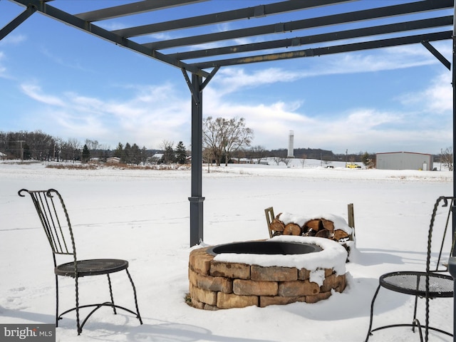 snow covered patio with a pergola and an outdoor fire pit