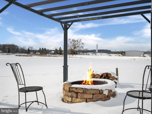 snow covered patio with a pergola and a fire pit