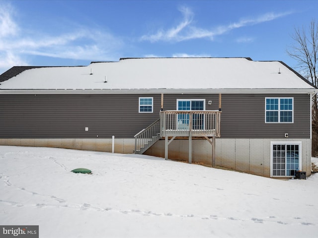 snow covered rear of property featuring a wooden deck