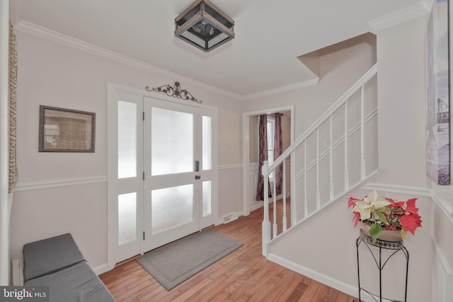 foyer entrance with ornamental molding and light hardwood / wood-style floors