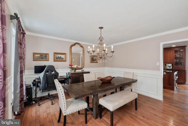 dining area featuring light hardwood / wood-style floors, ornamental molding, and a notable chandelier