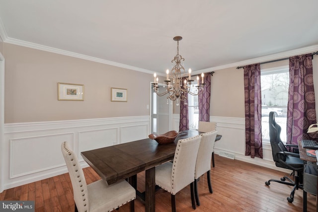 dining room with light wood-type flooring, ornamental molding, and an inviting chandelier