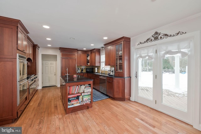 kitchen featuring stainless steel dishwasher, light wood-type flooring, ornamental molding, and a center island