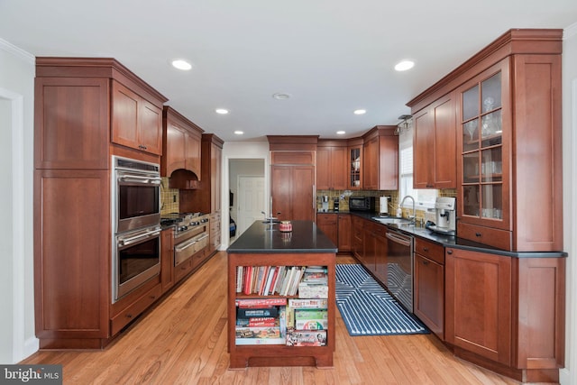 kitchen featuring appliances with stainless steel finishes, a kitchen island, sink, backsplash, and light hardwood / wood-style flooring