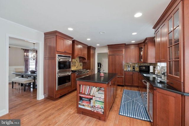 kitchen with a kitchen island, double oven, light hardwood / wood-style floors, sink, and a chandelier