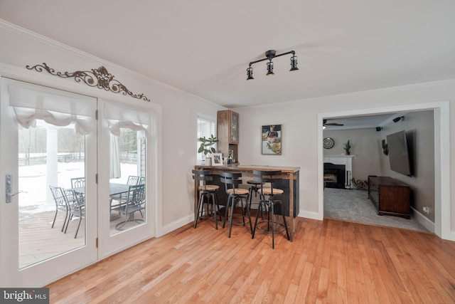 dining space with ceiling fan, rail lighting, crown molding, and light wood-type flooring