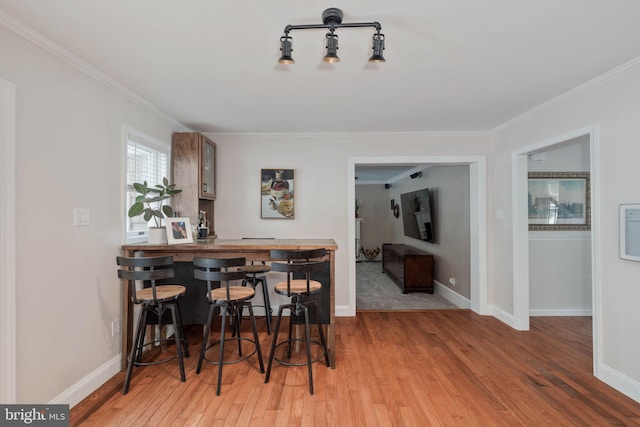 dining room featuring hardwood / wood-style floors, bar, and crown molding