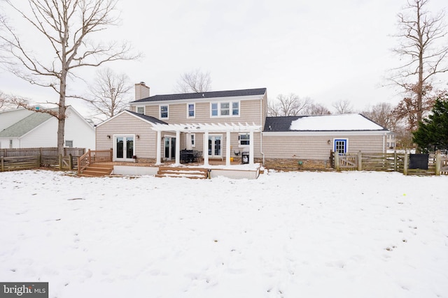 snow covered back of property featuring a pergola