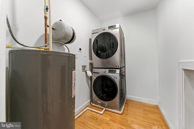 washroom featuring stacked washer / drying machine and hardwood / wood-style flooring