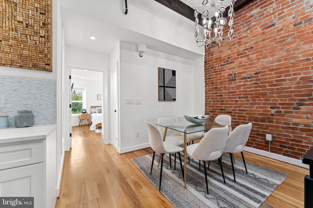 dining area with light hardwood / wood-style flooring, a chandelier, and brick wall