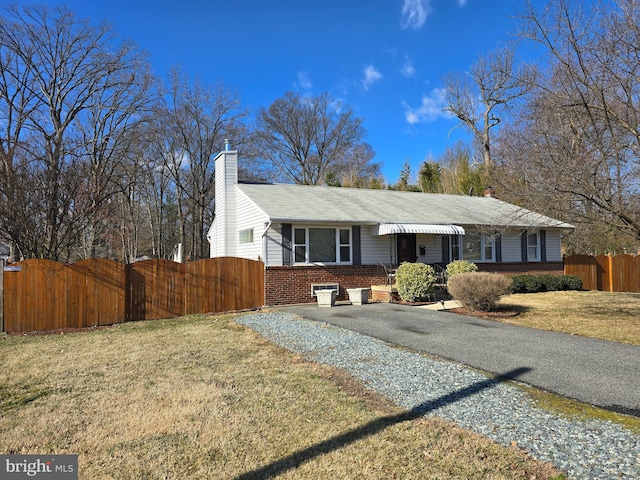 single story home with brick siding, a chimney, a front yard, and a fenced front yard