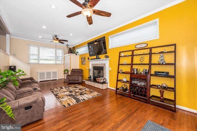 living area featuring ornamental molding, baseboards, a tiled fireplace, and wood finished floors