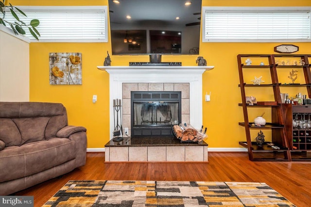 living room featuring baseboards, a tiled fireplace, and wood finished floors