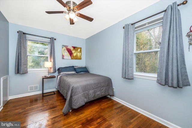 bedroom with multiple windows, visible vents, and dark wood finished floors