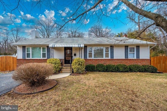 ranch-style home with a front yard, brick siding, and a chimney