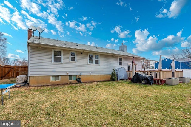 rear view of house with a yard, a chimney, and fence