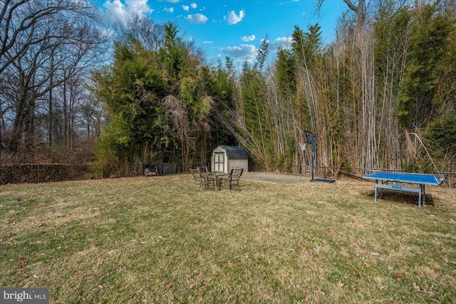 view of yard featuring a trampoline, a fenced backyard, an outdoor structure, and a storage unit